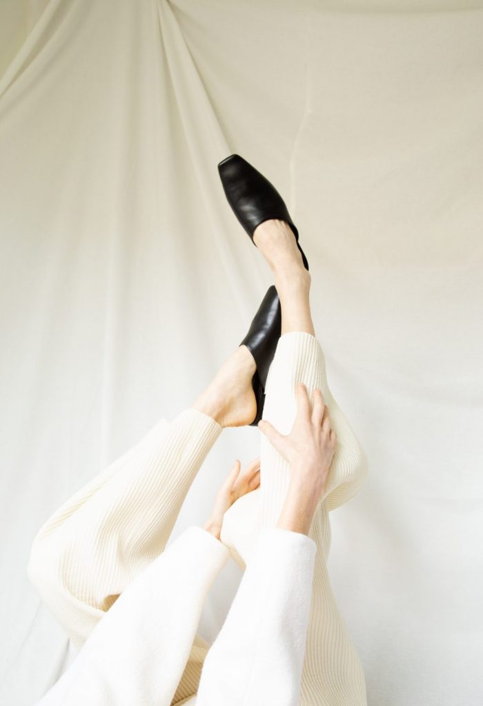 Bilde av beina til modellen, i ført hvit bukse og genser, med sorte sko.