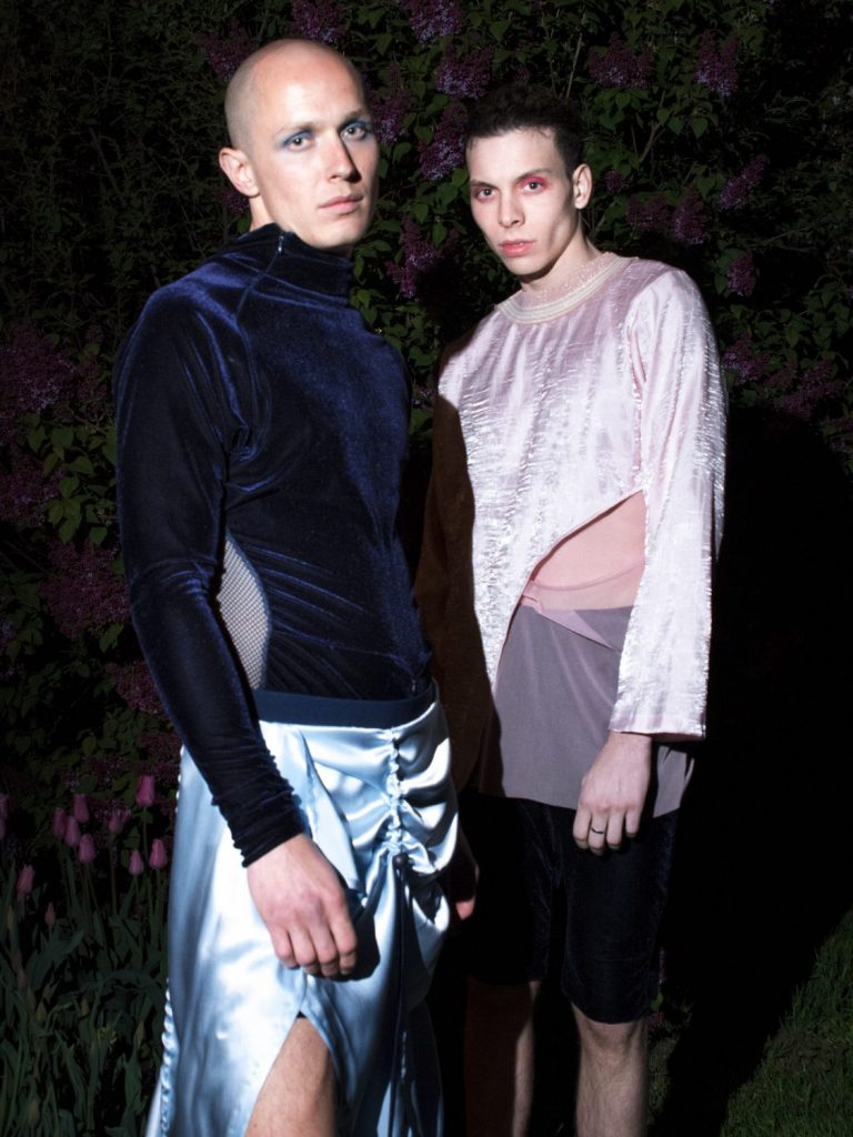 To mannlige modeller står iført et blått antrekk og et rosa antrekk.