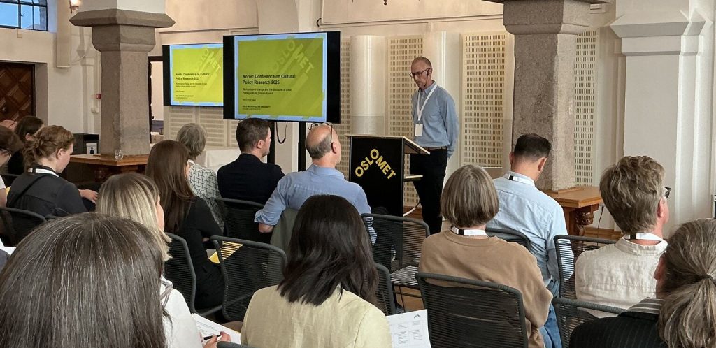 Håkon Larsen står foran forsamlingen og holder et innlegg.