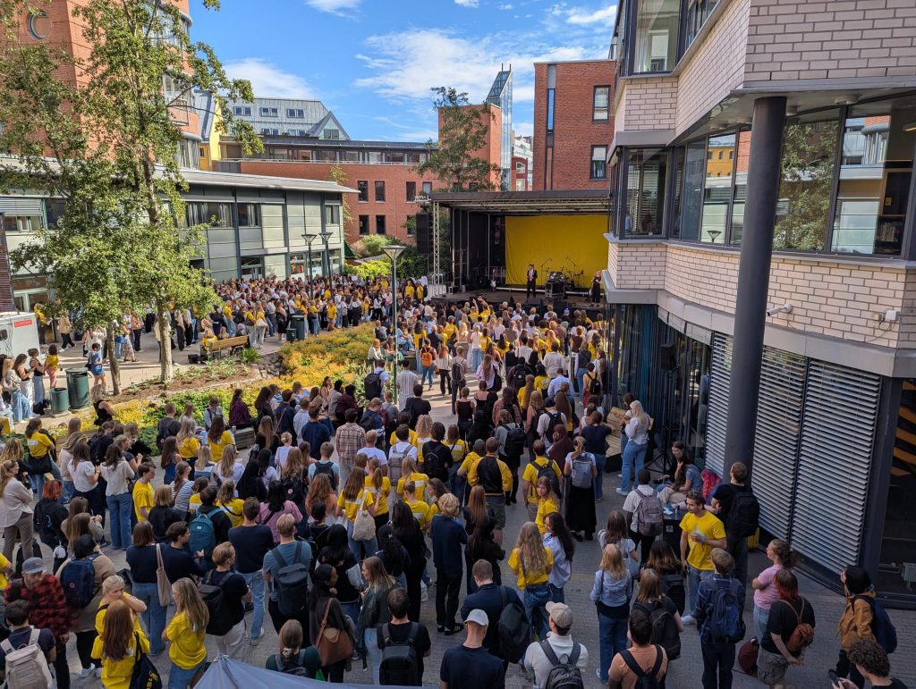 Velkomstsermoni mellom OsloMet sine bygg i Pilestredet. På scenen kan ein skimta rektor Christen Krogh. Det er mange nye studentar som står og ser mot scenen.