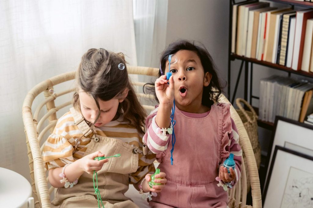 Two kids sitting making soap bubbles