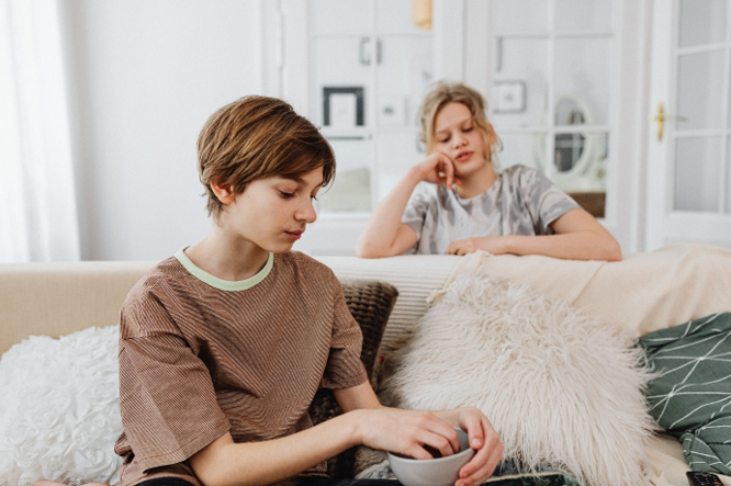 Picture of two teenagers hanging out in a living room.