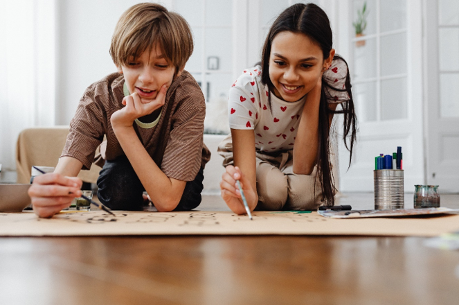 Picture of two teenagers painting a poster.