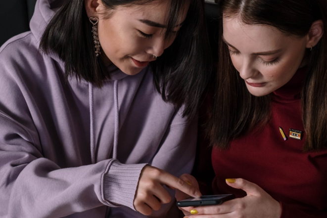 Picture of two girls looking at a phone.