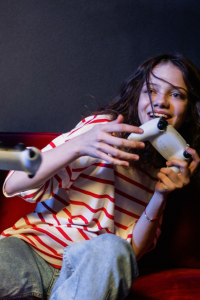 A girl laughing with a gaming controller in her hands.