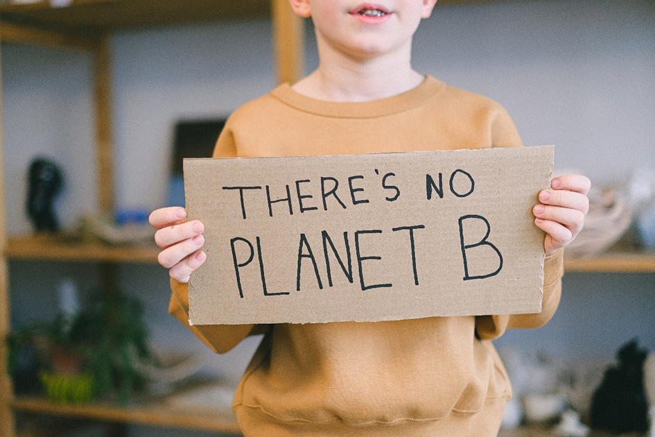 A boy holding a sign saying "There's no planet B"