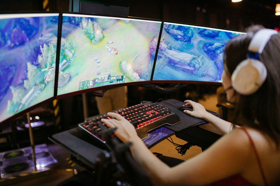 Girl gaming with three screens