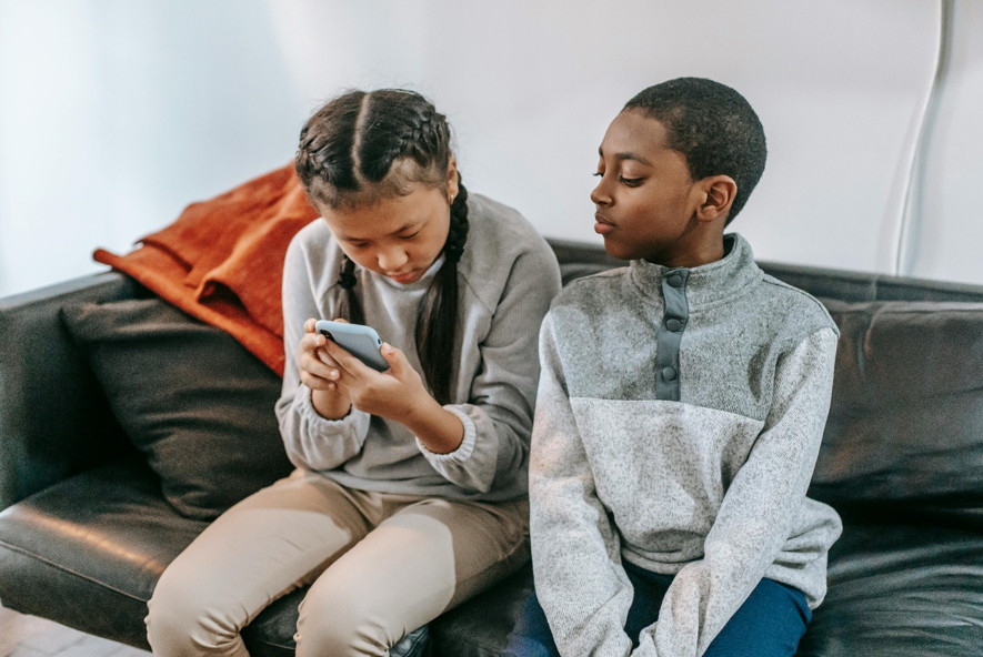 children sitting looking at a phone
