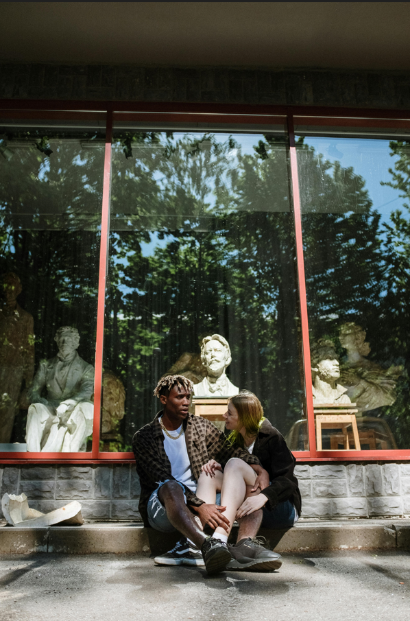 Two young people sitting close to each other in front of an art space