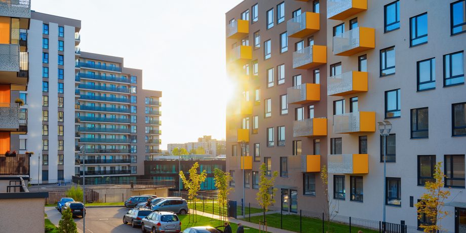 Leilighetsblokk med orange balkonger i solnedgang.