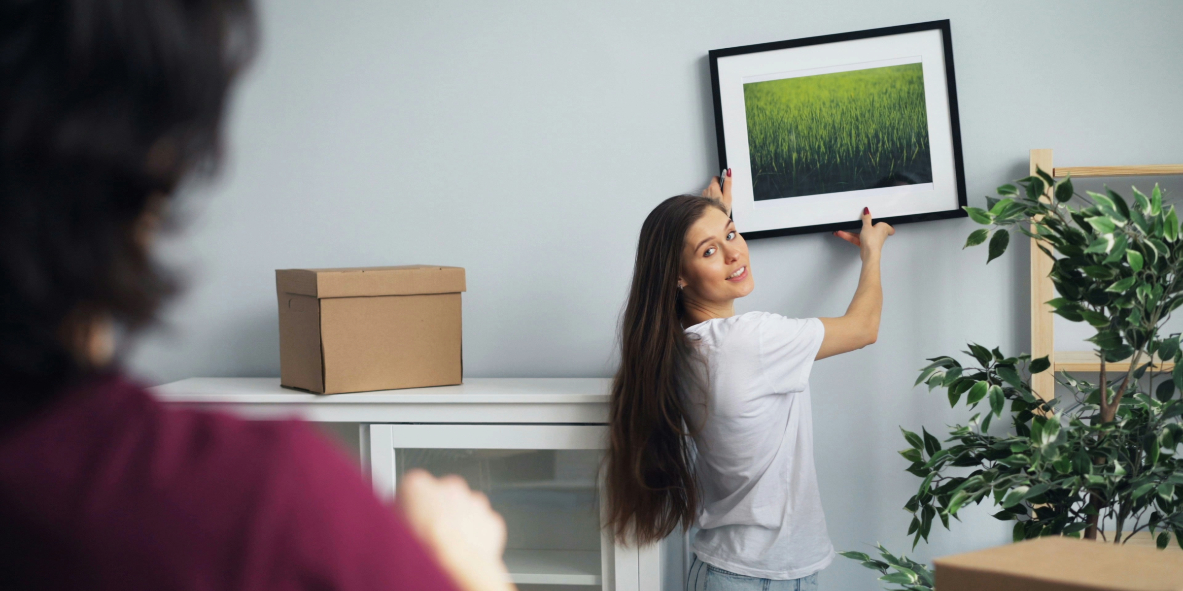 jente som har flyttet inn i leilighet og holder et bilde opp mot en vegg