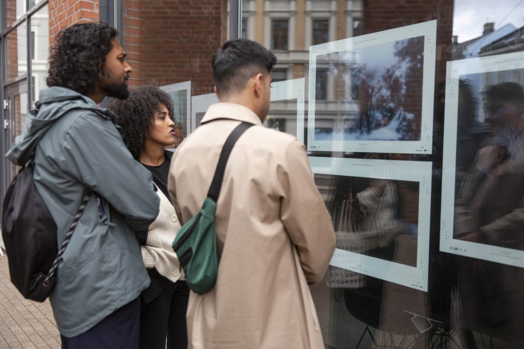 people watching the exhibition in front of a window.