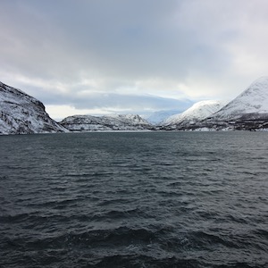 Bilde fra prosjektet til Hanne Kjærland Olsen. Utsikt over Kåfjord, Alta kommune. Mørkeblått hav og fjell dekket med snø. 