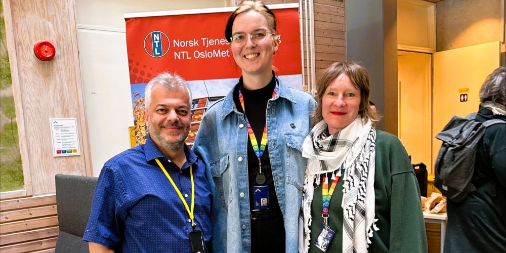 Bilde av 3 stykker oppstilt foran NTL logo