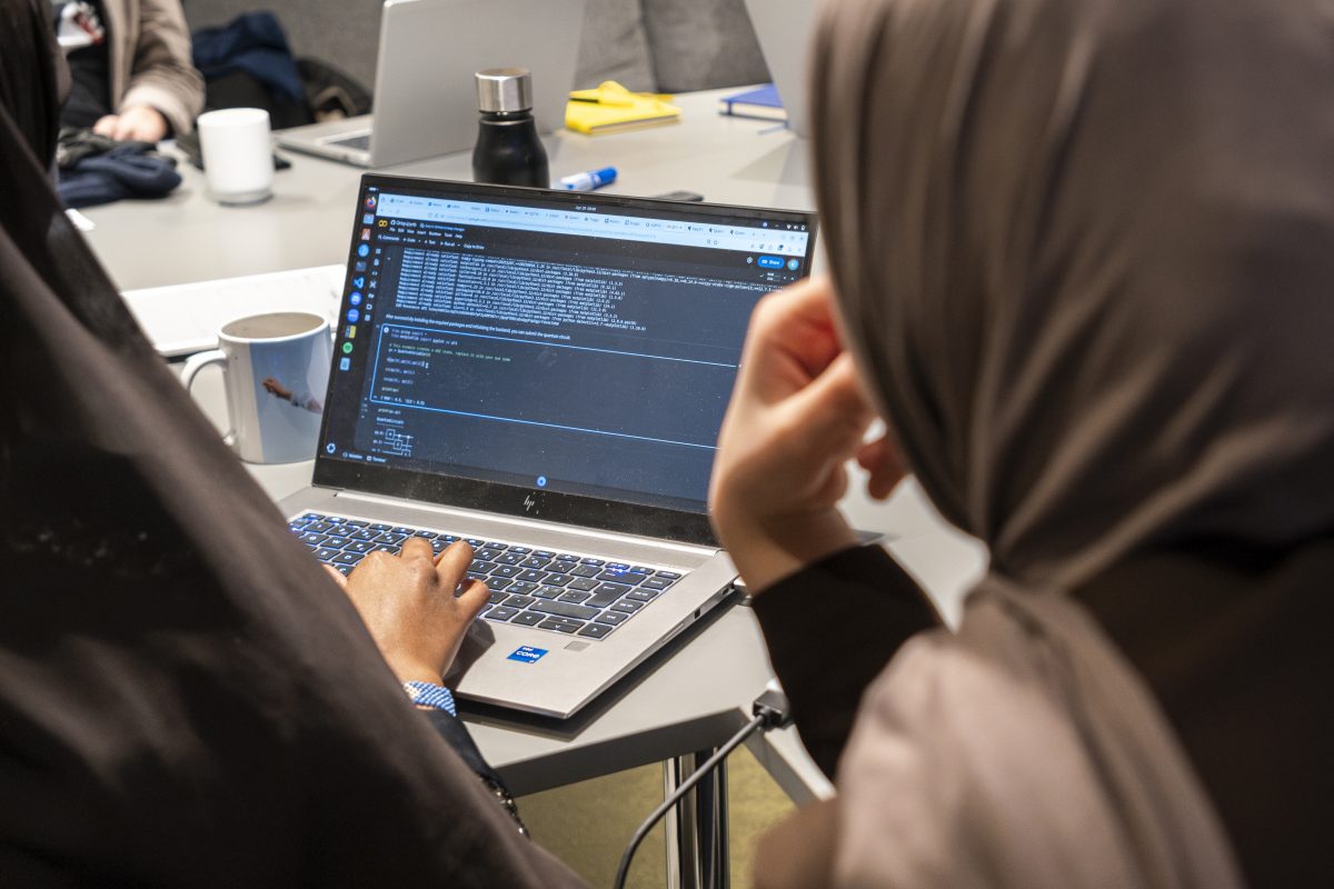Two girls looking at code on a computer.