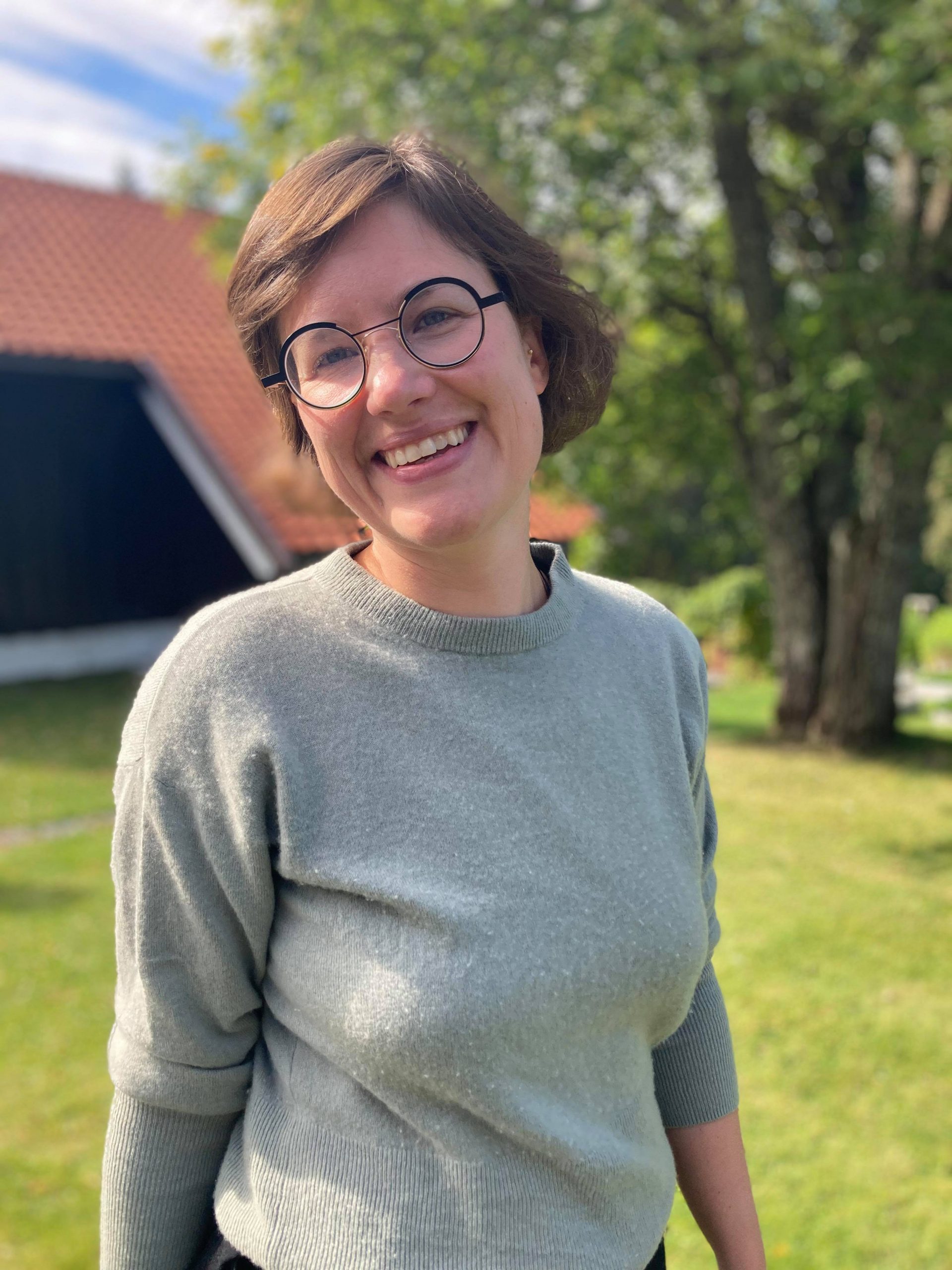 Portrait photo of Anne Balke Staver, in a turqouise sweater and glasses.