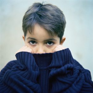 Foto av ung gutt med ansikt delvis skjult av høyhalset genser. Direkte blikk. Illustrasjonsfoto: colourbox.no