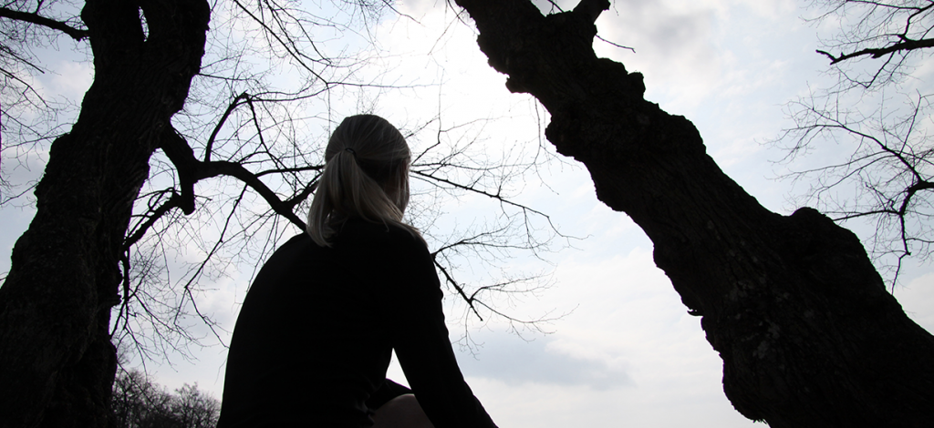 Mørk silhuett av ung kvinne mot mørke trær. colourbox.com