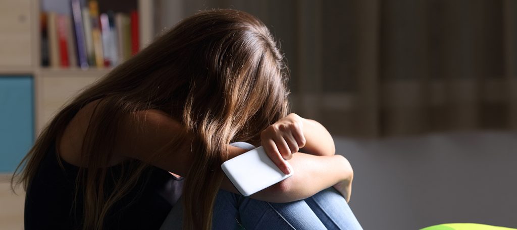 Ung jente sitter med hodet begravd i fanget