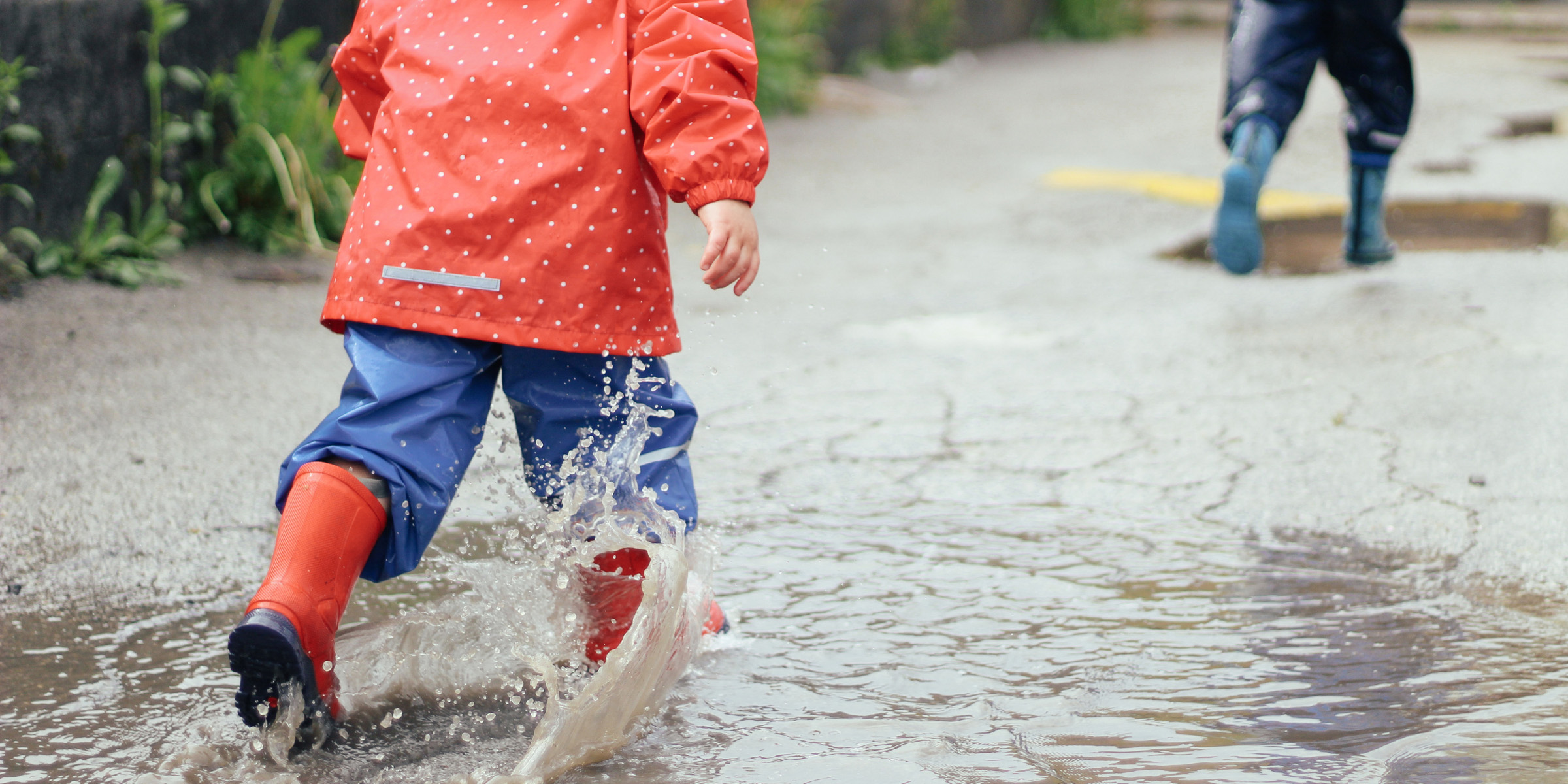 Små barn sett bakgra løper gjennom sølepytter