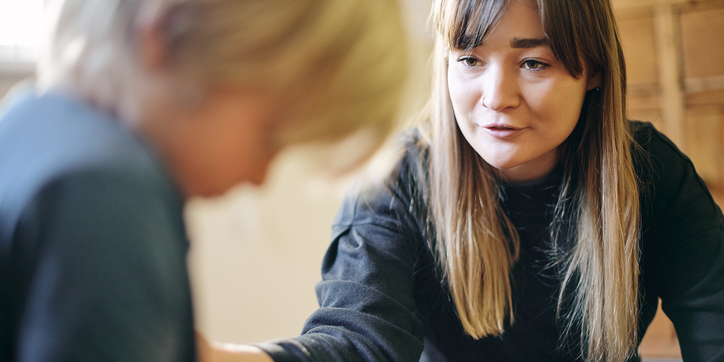 Vaksen kvinne snakkar med eit barn som er i utydelig silhouette